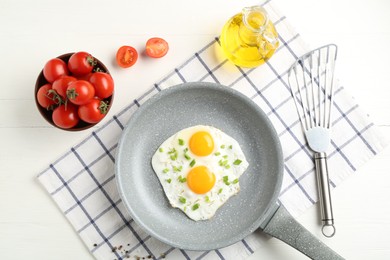 Photo of Tasty fried eggs with green onion in frying pan, oil and tomatoes on white wooden table, flat lay