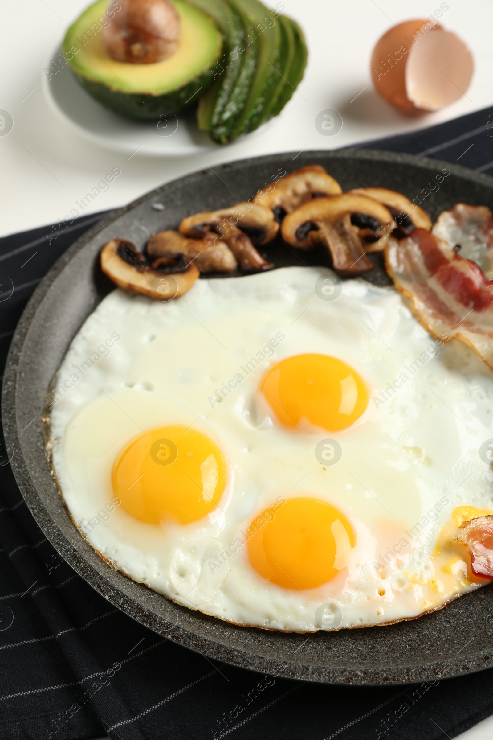 Photo of Tasty fried eggs with bacon and mushrooms served on table, closeup