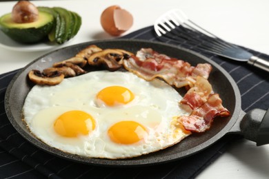 Photo of Tasty fried eggs with bacon and mushrooms served on white table, closeup