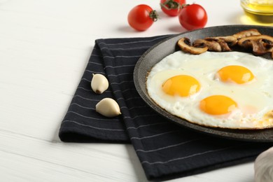 Photo of Tasty fried eggs with mushrooms served on white wooden table, closeup. Space for text