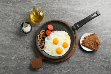 Photo of Tasty fried eggs with mushrooms served on grey table, flat lay