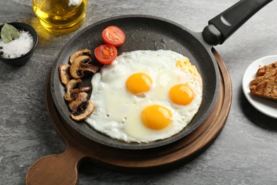 Photo of Tasty fried eggs with mushrooms served on grey table