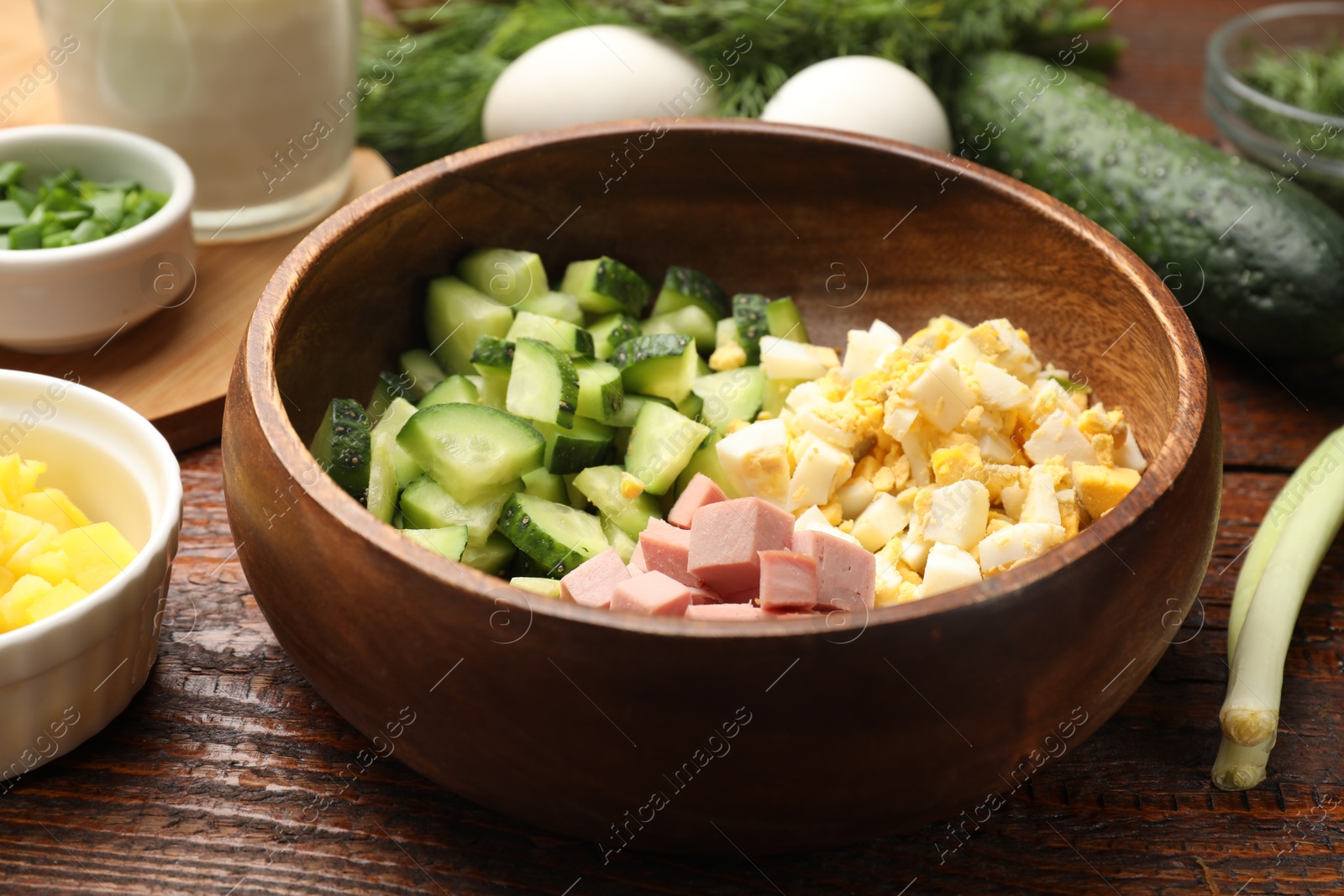 Photo of Different ingredients for okroshka soup on wooden table, closeup