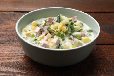 Photo of Delicious okroshka soup in bowl on wooden table, closeup