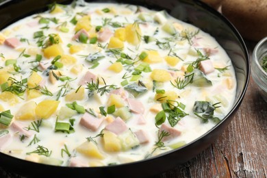 Photo of Delicious okroshka soup with kefir in bowl on wooden table, closeup