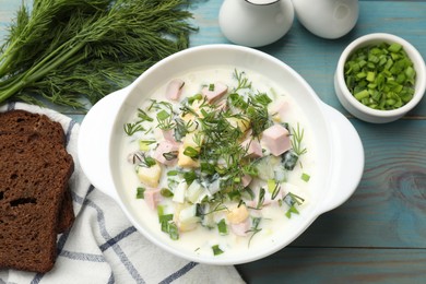 Photo of Delicious okroshka soup served on light blue wooden table, flat lay