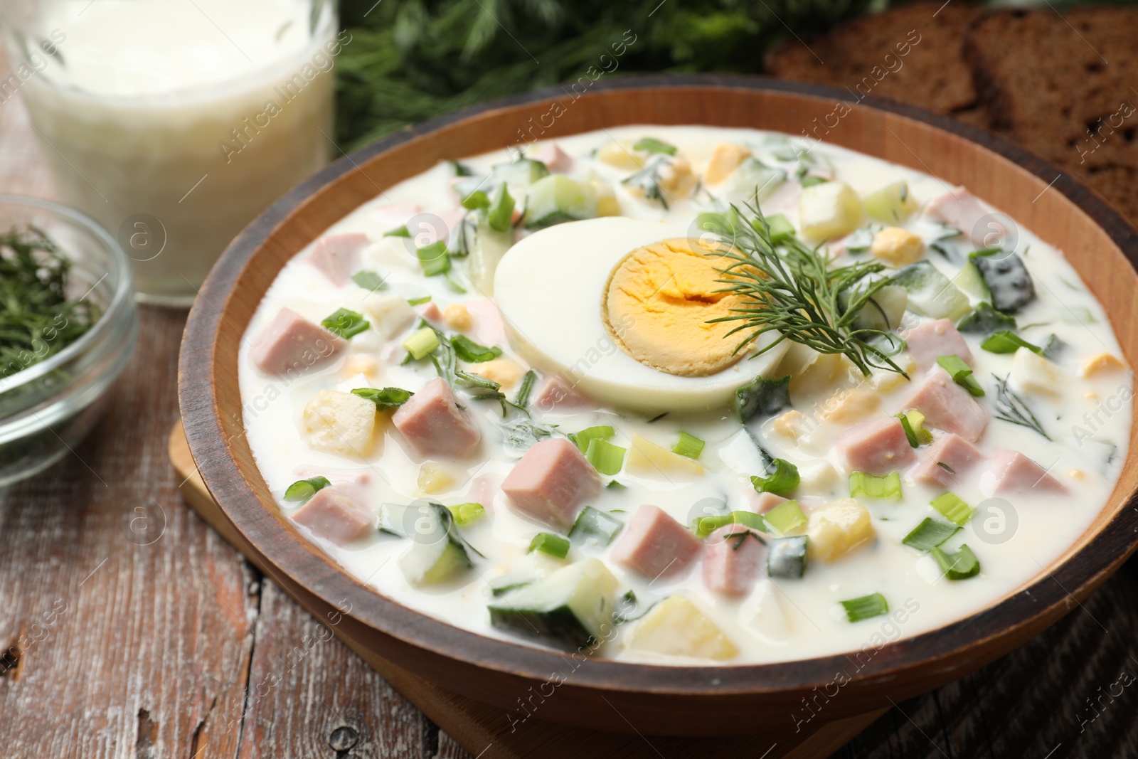 Photo of Delicious okroshka soup with kefir served on wooden table, closeup