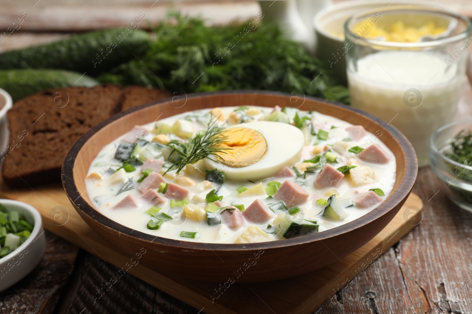 Photo of Delicious okroshka soup with kefir served on wooden table, closeup