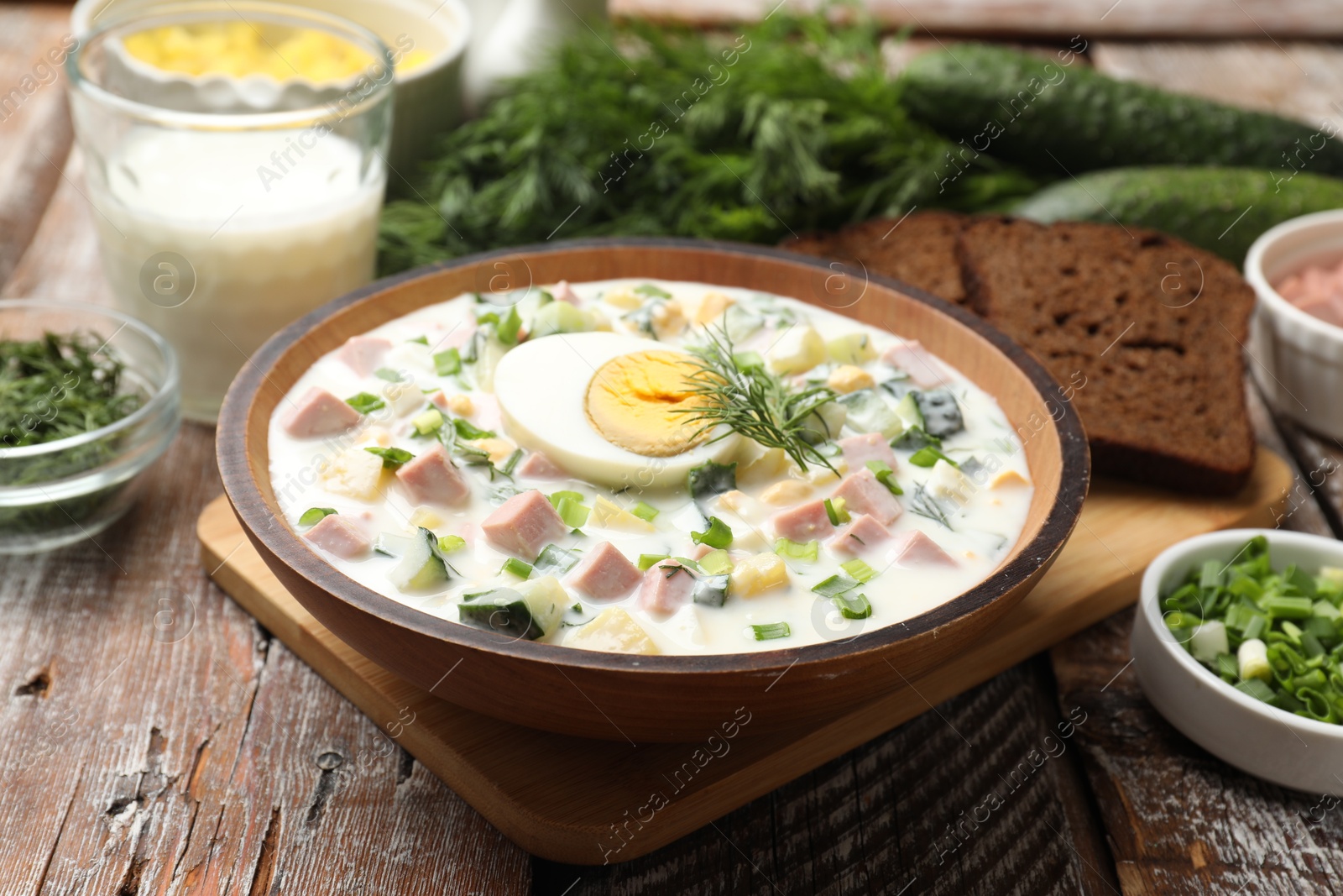 Photo of Delicious okroshka soup with kefir served on wooden table, closeup