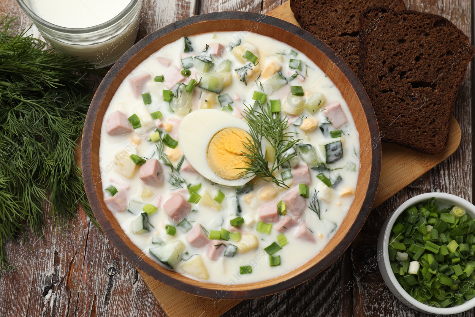 Photo of Delicious okroshka soup with kefir served on wooden table, flat lay