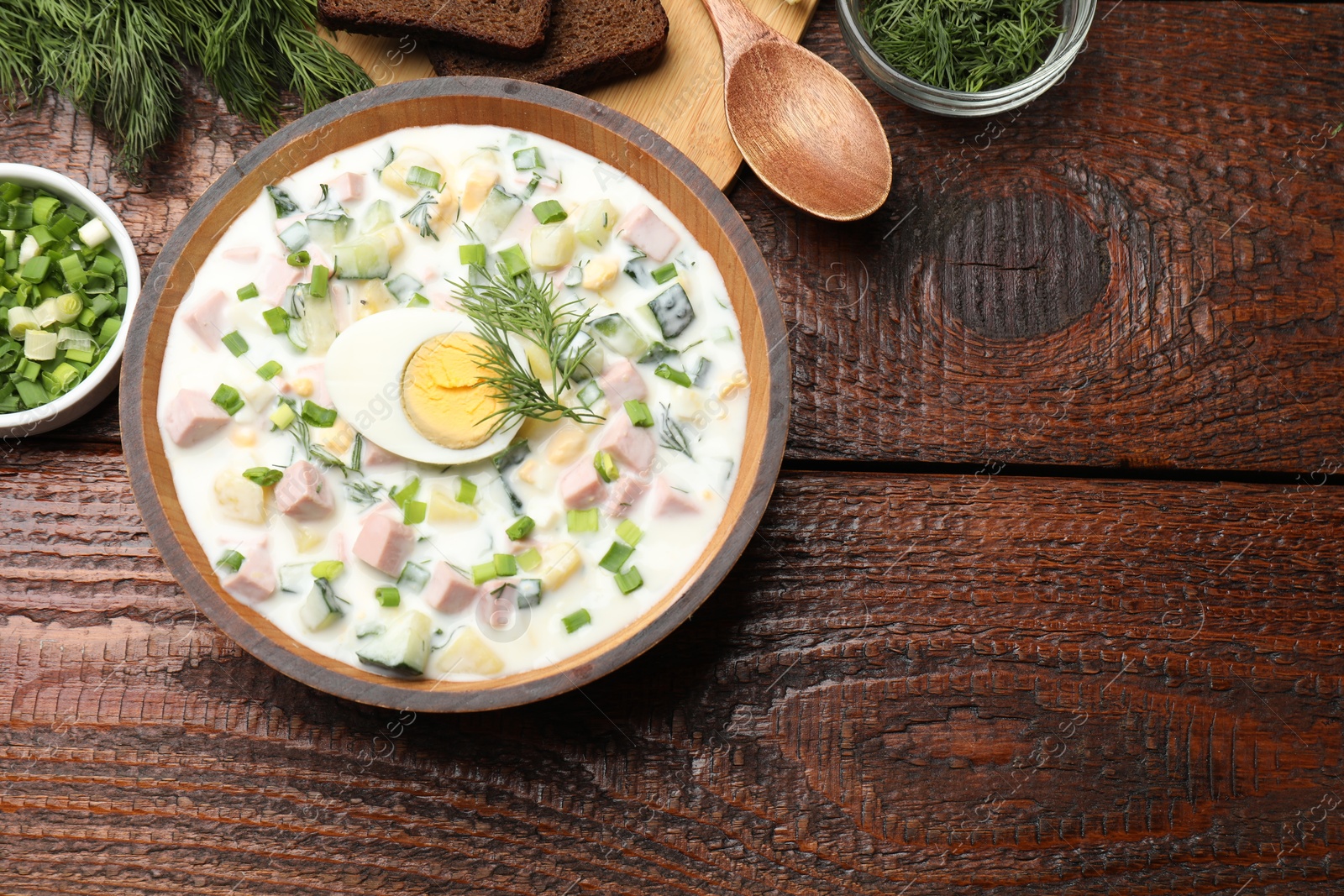 Photo of Delicious okroshka soup with kefir served on wooden table, flat lay. Space for text