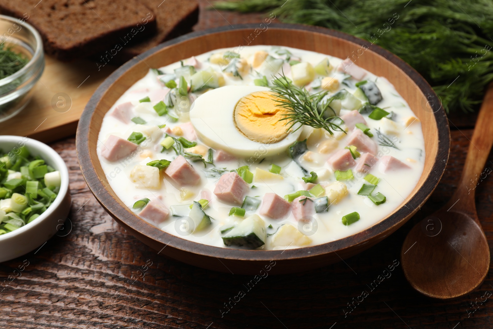 Photo of Delicious okroshka soup with kefir served on wooden table, closeup