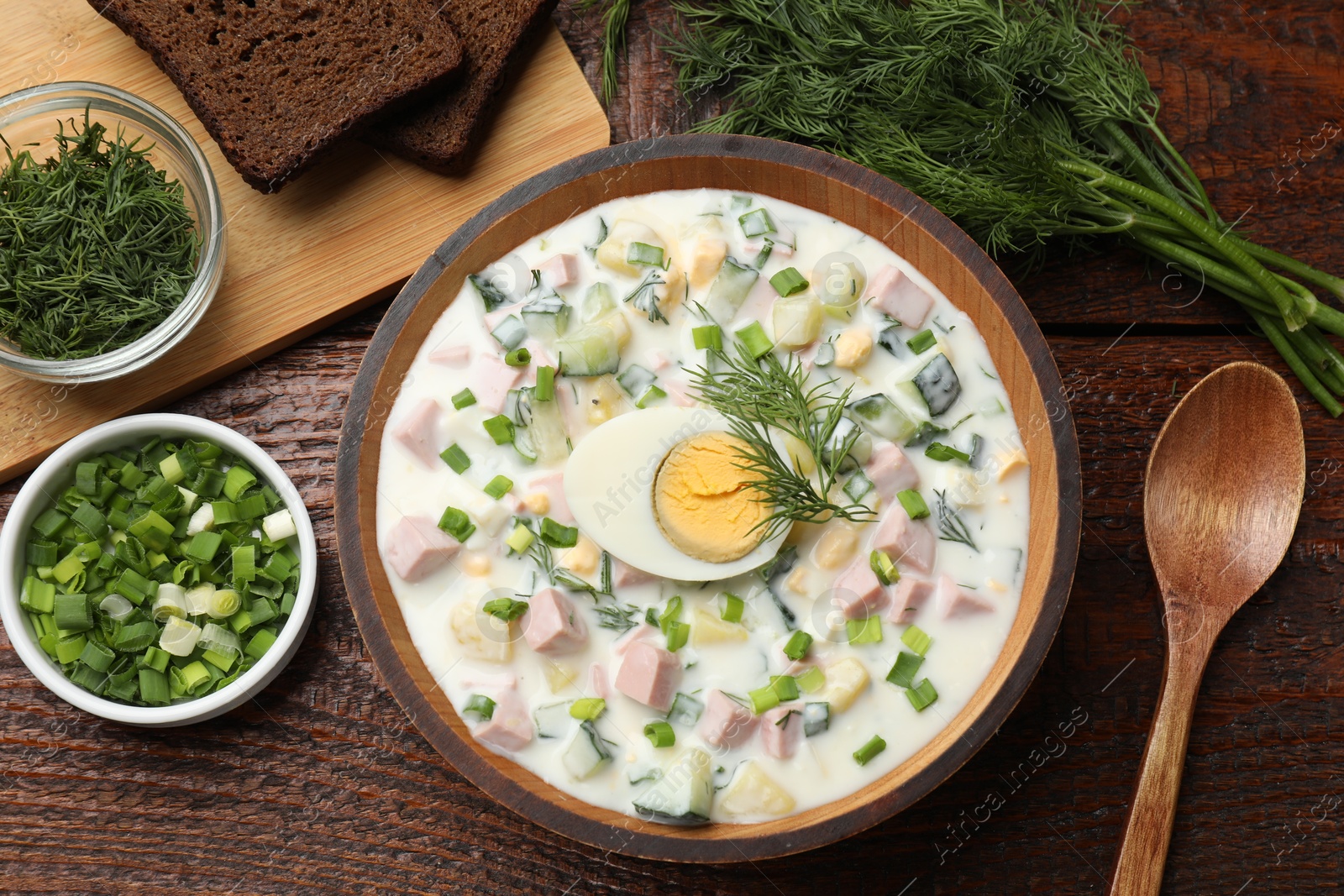 Photo of Delicious okroshka soup with kefir served on wooden table, flat lay