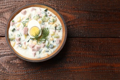 Photo of Delicious okroshka soup with kefir in bowl on wooden table, top view. Space for text