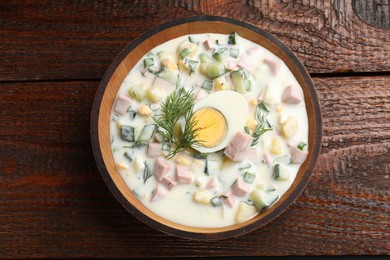 Photo of Delicious okroshka soup with kefir in bowl on wooden table, top view