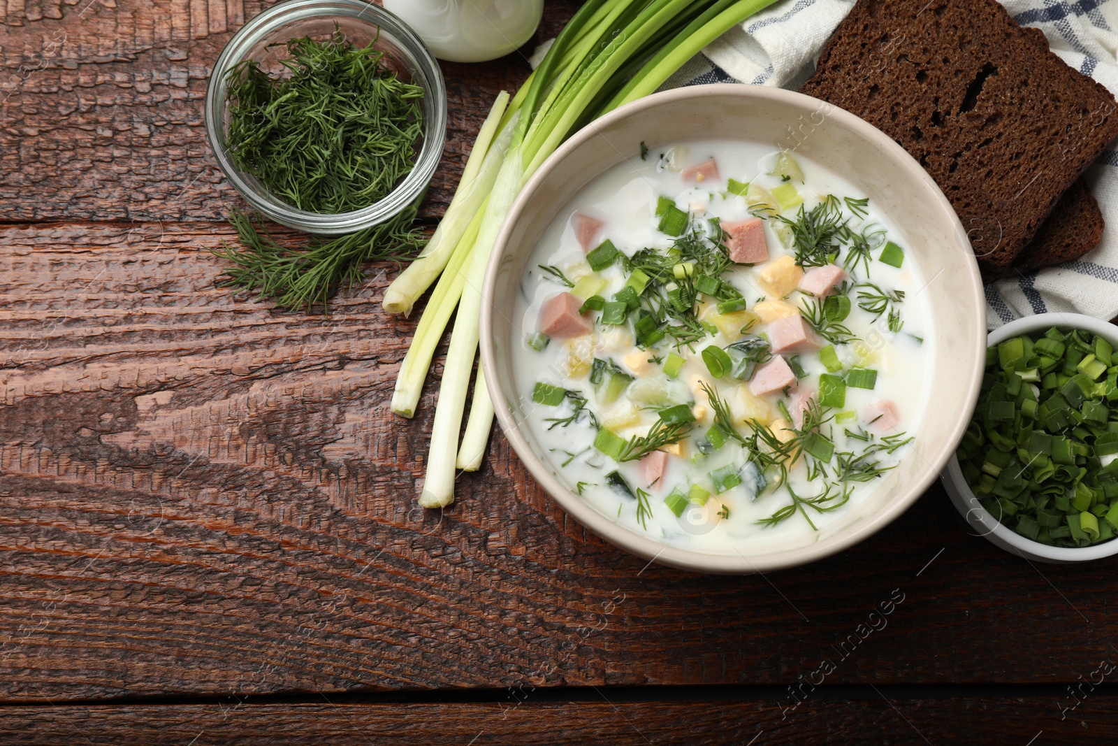 Photo of Delicious okroshka soup with kefir served on wooden table, flat lay. Space for text