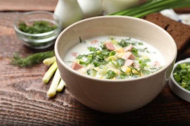 Photo of Delicious okroshka soup with kefir served on wooden table, closeup