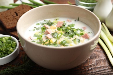 Photo of Delicious okroshka soup with kefir served on wooden table, closeup