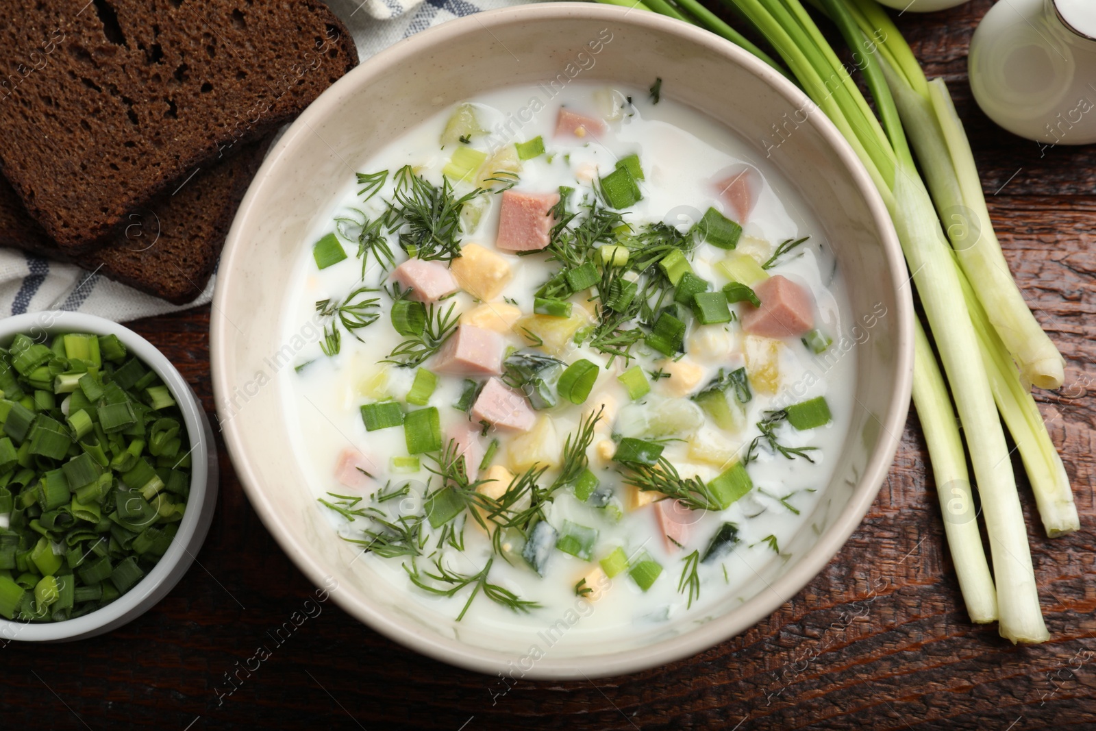 Photo of Delicious okroshka soup with kefir served on wooden table, flat lay