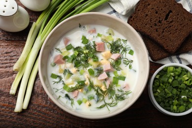 Photo of Delicious okroshka soup with kefir served on wooden table, flat lay