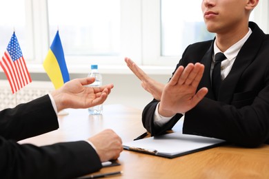 Photo of Diplomats negotiating during meeting at wooden table indoors, closeup