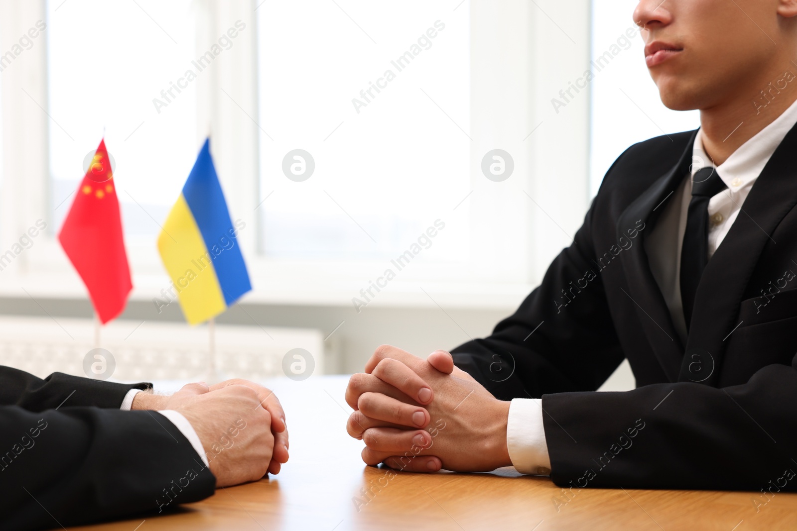 Photo of Diplomats negotiating during meeting at wooden table indoors, closeup