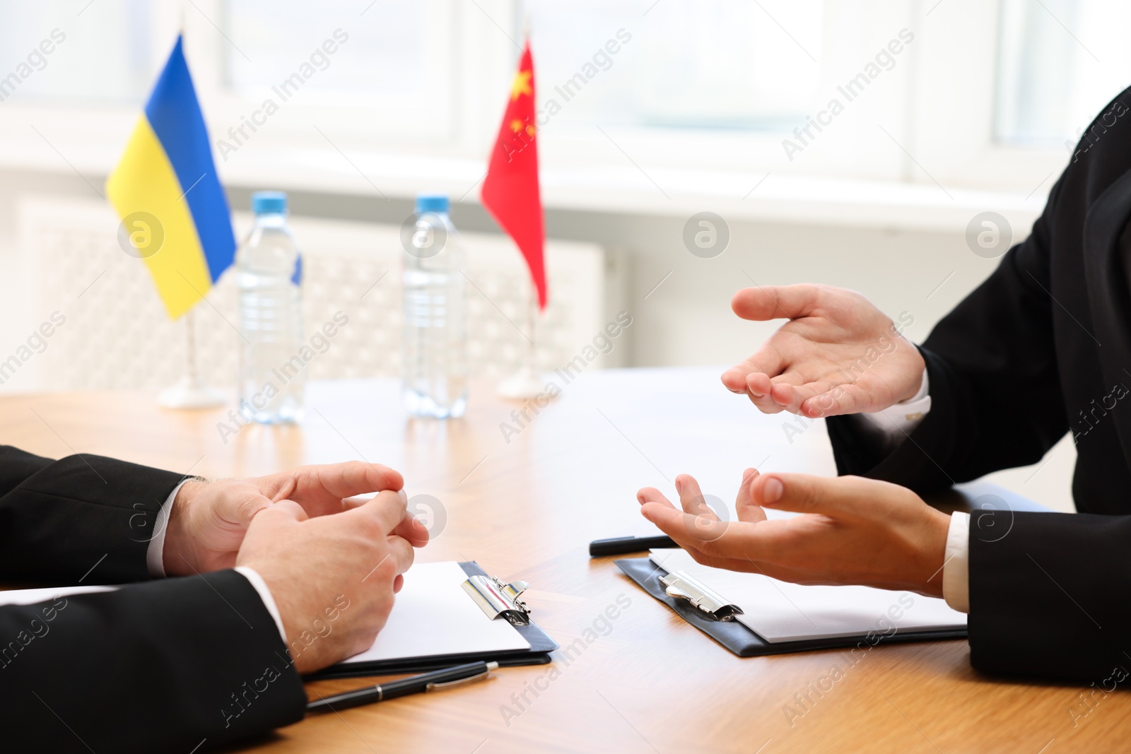 Photo of Diplomats negotiating during meeting at wooden table indoors, closeup