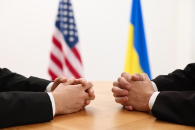 Photo of Diplomats negotiating during meeting at wooden table indoors, closeup