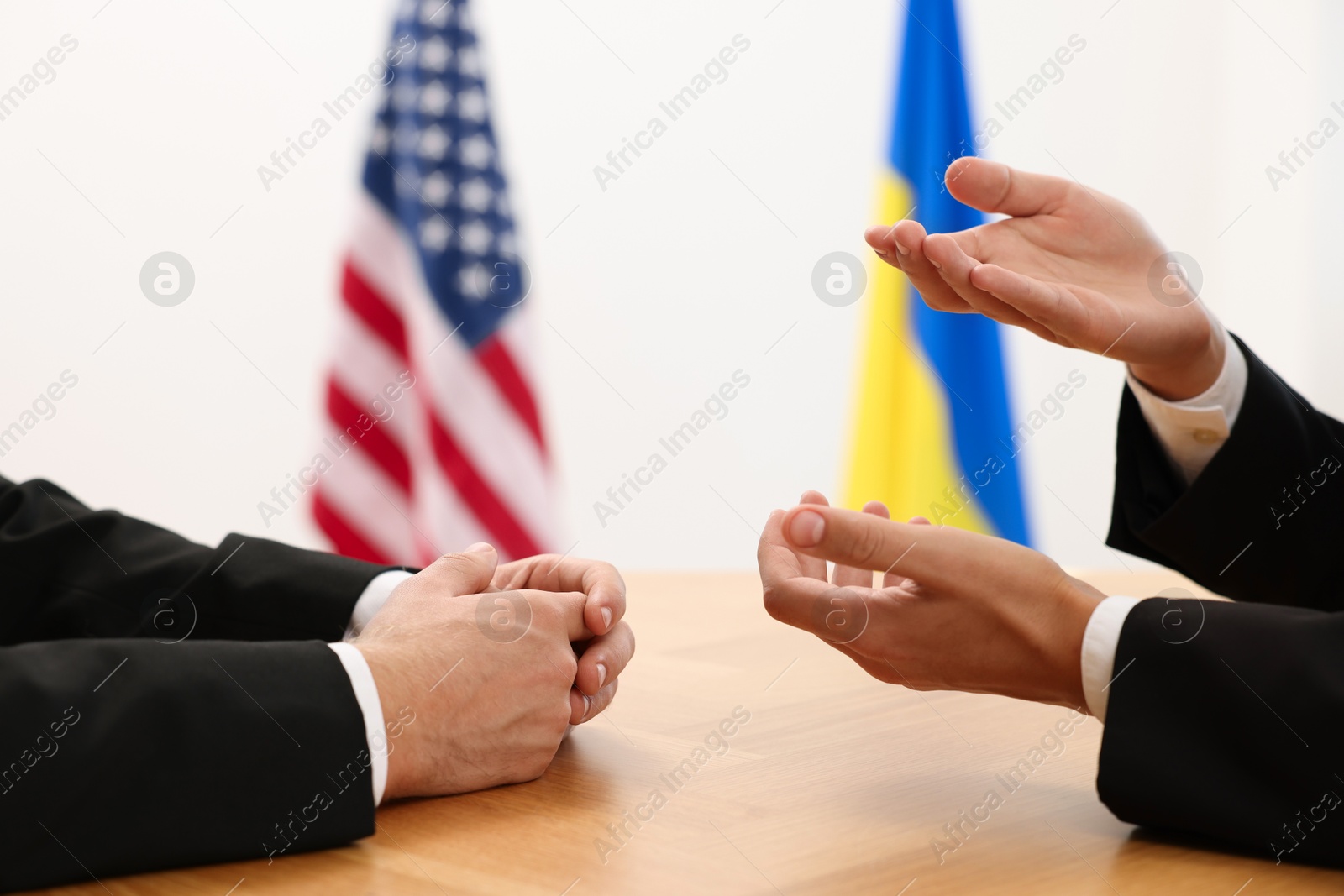 Photo of Diplomats negotiating during meeting at wooden table indoors, closeup