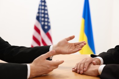 Photo of Diplomats negotiating during meeting at wooden table indoors, closeup