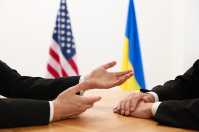 Photo of Diplomats negotiating during meeting at wooden table indoors, closeup