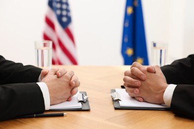 Photo of Diplomats negotiating during meeting at wooden table indoors, closeup