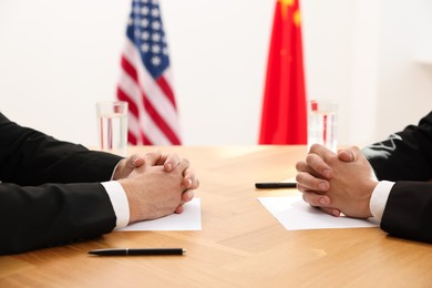 Photo of Diplomats negotiating during meeting at wooden table indoors, closeup