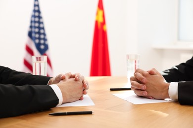 Photo of Diplomats negotiating during meeting at wooden table indoors, closeup