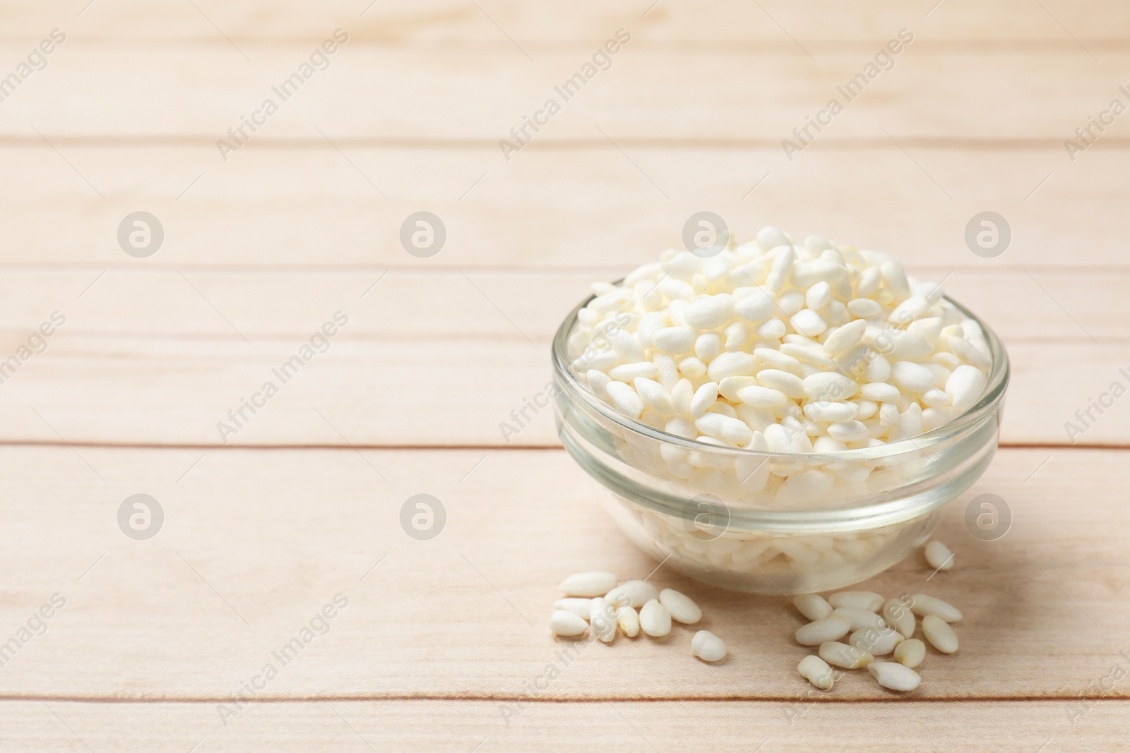 Photo of Puffed rice in bowl on white wooden table, closeup. Space for text