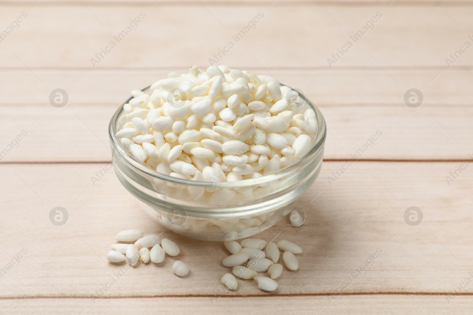 Photo of Puffed rice in bowl on white wooden table, closeup