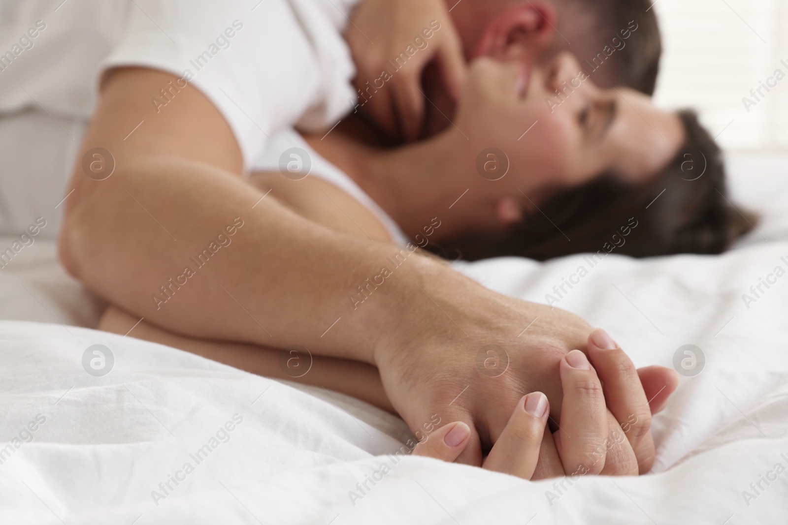 Photo of Lovely couple holding hands in bed, selective focus