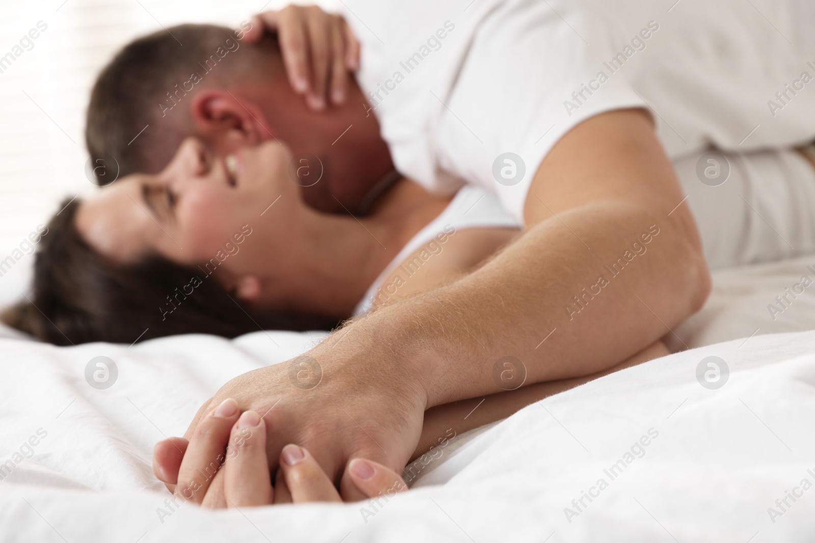 Photo of Lovely couple holding hands in bed, selective focus