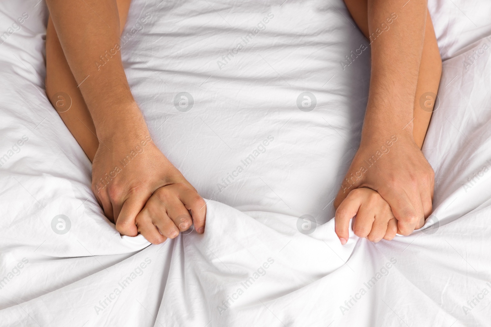 Photo of Lovely couple holding hands in bed, top view