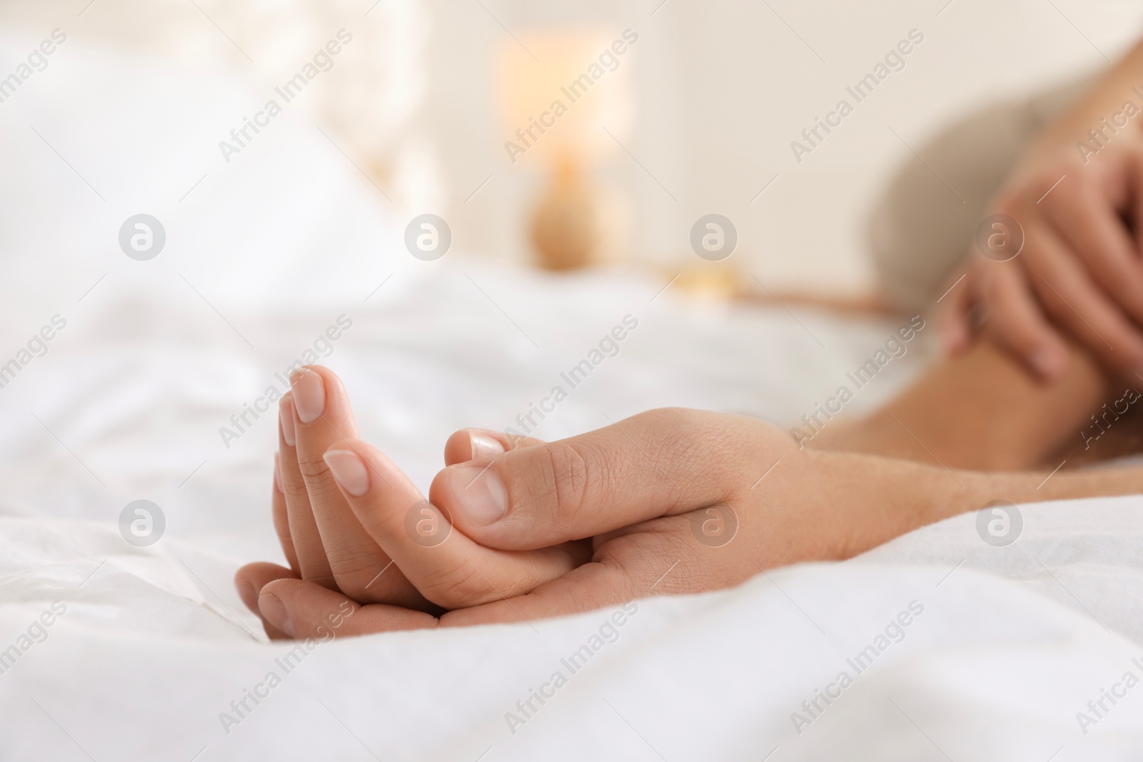 Photo of Lovely couple holding hands in bed, closeup