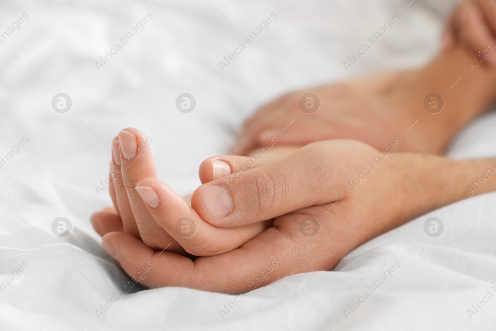 Photo of Lovely couple holding hands in bed, closeup