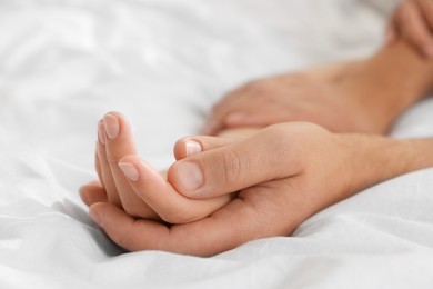 Photo of Lovely couple holding hands in bed, closeup