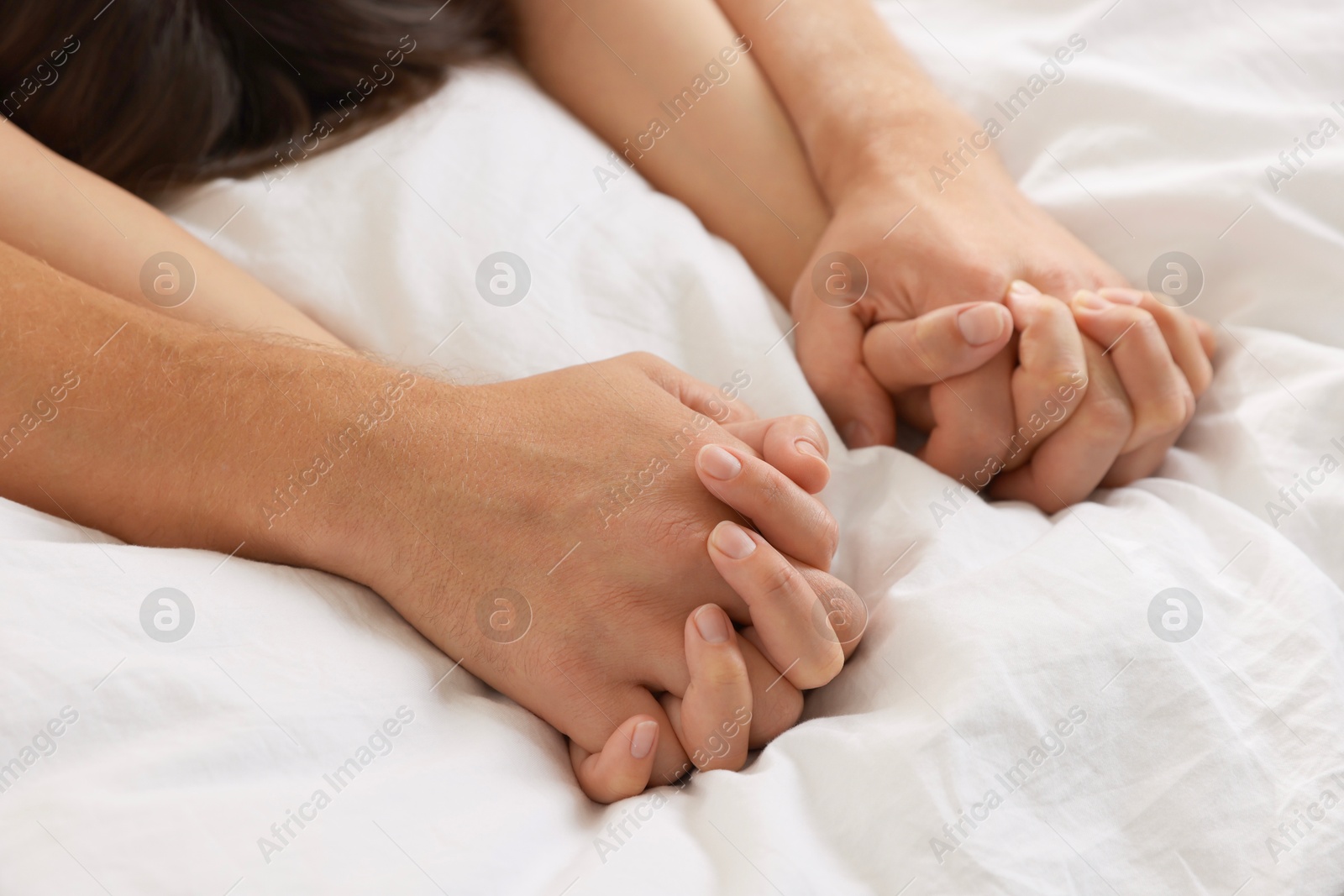 Photo of Lovely couple holding hands in bed, closeup