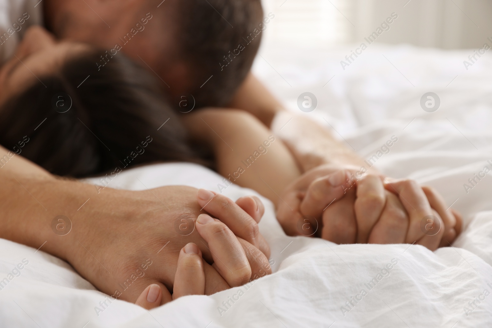 Photo of Lovely couple holding hands in bed, closeup