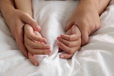 Photo of Lovely couple holding hands in bed, closeup