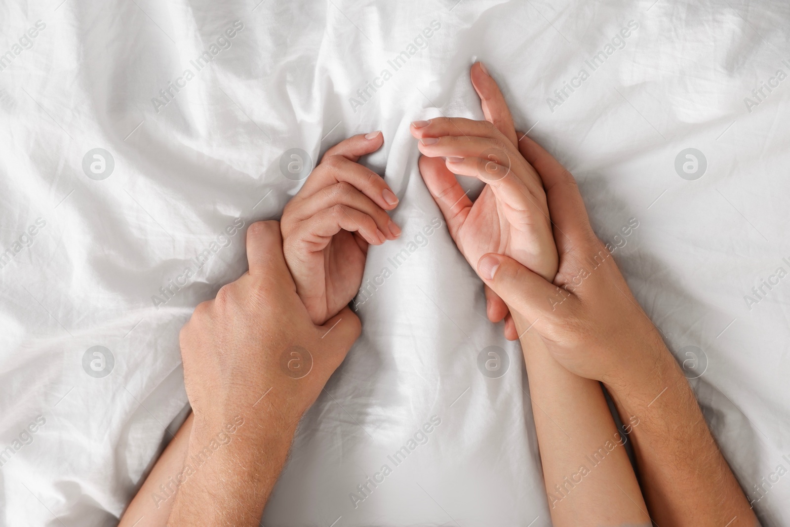 Photo of Lovely couple holding hands in bed, top view