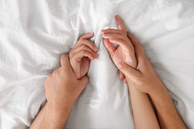 Photo of Lovely couple holding hands in bed, top view