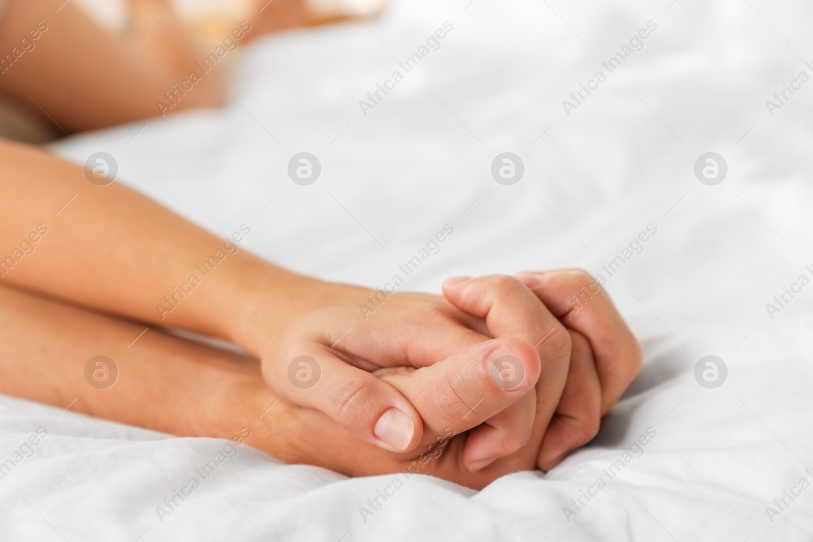 Photo of Lovely couple holding hands in bed, closeup