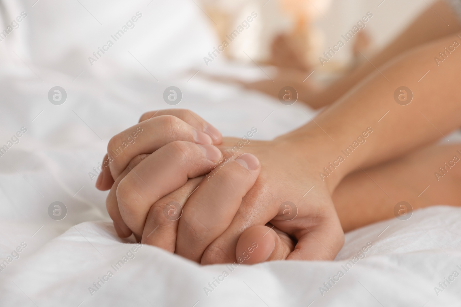 Photo of Lovely couple holding hands in bed, closeup