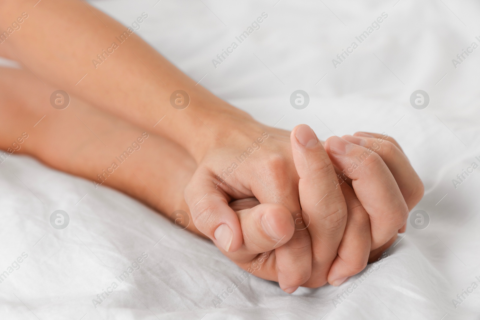 Photo of Lovely couple holding hands in bed, closeup